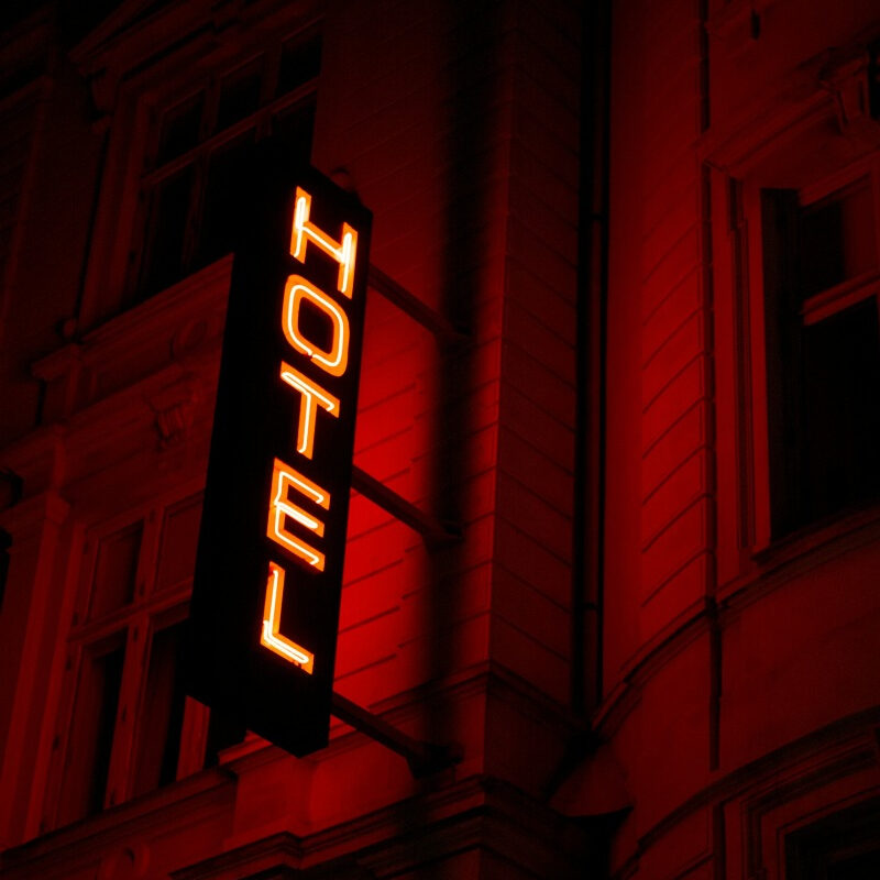 Cartel luminoso rojo con la palabra HOTEL.