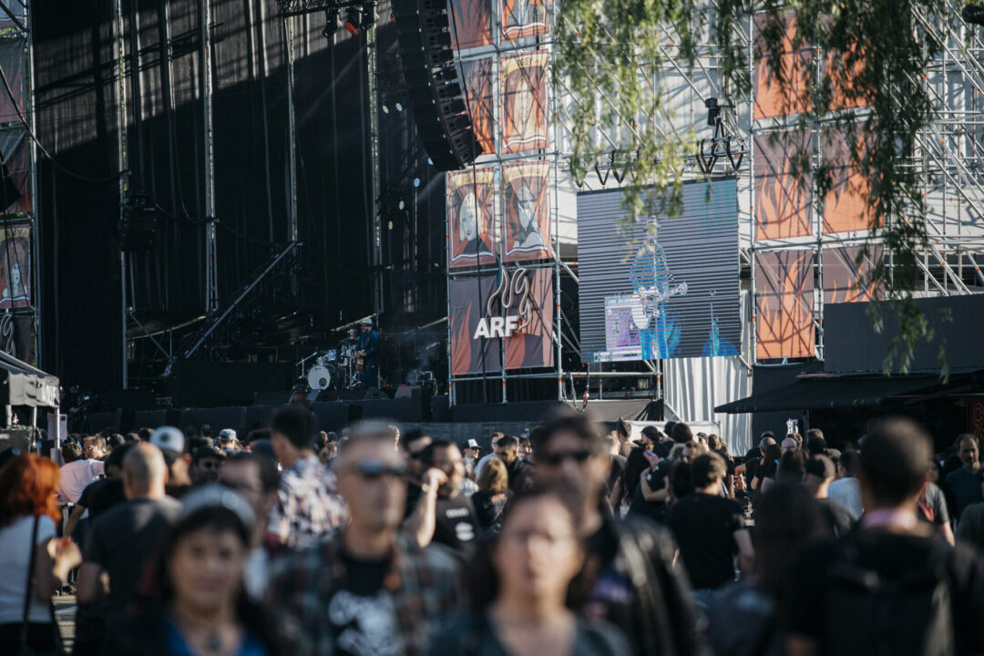 Escenario del festival Azkena Rock Festival (ARF) con público en primer plano y pantallas mostrando la actuación de un músico.