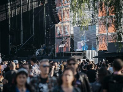 Escenario del festival Azkena Rock Festival (ARF) con público en primer plano y pantallas mostrando la actuación de un músico.